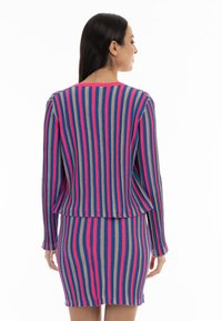 Conjunto de cárdigan y falda a rayas con patrones en azul, rosa y beige. Textura suave con un corte relajado y mangas largas.