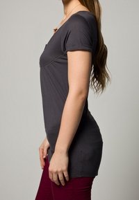 Grå kortärmad topp med rundad halsringning, figursydd passform och slät textur, kombinerad med vinröda byxor, sedd från sidan.