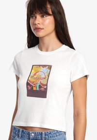 Cropped white t-shirt made of cotton, featuring a colorful graphic print of a mushroom with abstract shapes and a dark brown accent.