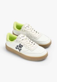Baskets en cuir blanc avec doublure vert vif, présentant un design de skull et os croisés noirs, et une semelle en caoutchouc beige. Fermeture à lacets.