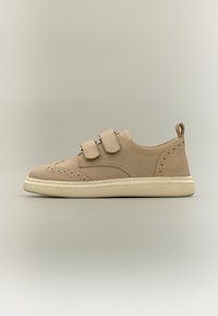 Μπεζ καστόρινο καθημερινό αθλητικό παπούτσι με δύο λουράκια βέλκρο, διακοσμητικές περφορέσεις και κρέμ λαστιχένια σόλα σε ουδέτερο φόντο.