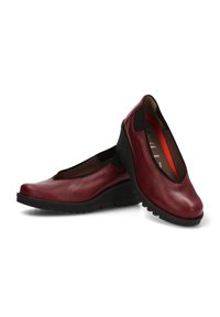 Bailarinas de cuero rojo con punta redondeada y paneles laterales elásticos, que cuentan con un tacón bajo en forma de cuña y una suela de goma negra con textura.