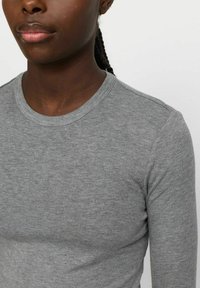 T-shirt grigia a maniche lunghe realizzata in morbido tessuto di cotone, con scollo rotondo, texture sottile e spalle senza cuciture.