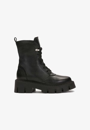 Fekete, fűzős bokacsizma textúrált bőrből, tömör platform talppal, amelyen kivágások találhatók, valamint hátsó húzószíjjal.