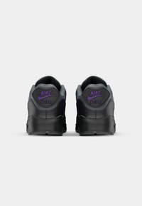 Black sneakers with purple accents, featuring a padded collar, textured heel, and large logo on the back. Smooth synthetic material.