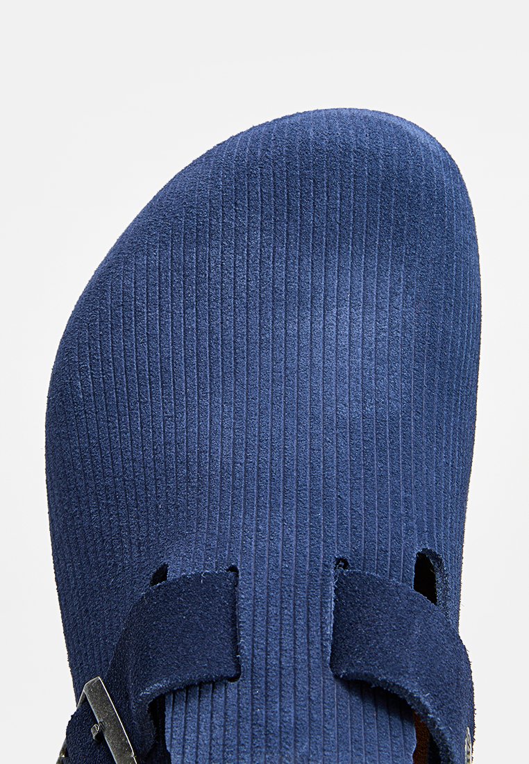 Navy blaue Wildleder-Sandale mit gerippter Textur, verstellbaren Riemen und einem metallischen Schnallenakzent für einen sicheren Sitz.