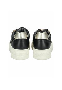 Baskets en cuir noir avec un accent argenté au talon, une semelle en caoutchouc blanche texturée et des fermetures éclair sur le côté pour un enfilage facile.