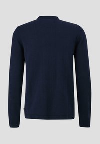 Granatowy sweter z długim rękawem i okrągłym dekoltem, wykonany z gładkiego materiału, o minimalistycznym wzorze z subtelną metką na dolnym wykończeniu.