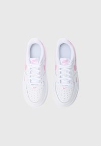 Valged tossud roosade detailidega, mis on valmistatud siledast nahast pealispinna, perforatsiooniga varbale, ümarate kujude ja lamedate paeltega. Nike kaubamärk on nähtav.