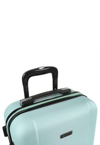 Maleta dura en verde menta con acabado texturizado, mango retráctil negro y cremalleras dobles. Presenta una base plana para mayor estabilidad.