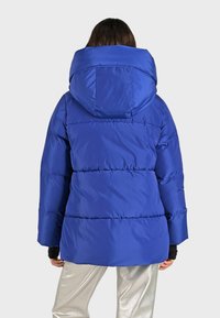 Blauwe pufferjack met een grote capuchon, gequilt ontwerp en ruime mouwen. De stof heeft een gladde, glanzende textuur.
