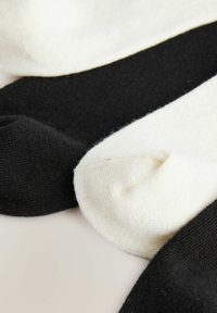 Katoenen sokken in zwart en crème, met een soepele textuur, klassieke vorm en contrasterende kleuren. Rubberaccenten voor duurzaamheid.