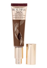 Charlotte's Beautiful Skin Foundation tube in dark shade with gold pump and cap, labeled for healthy, daily skin use.
