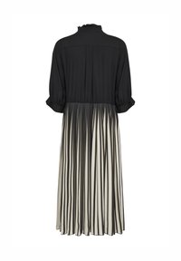 Čierny top s volánovým golierom, plisovaná sukňa s čierno-bielymi pruhmi, dlhé rukávy a voľný strih.