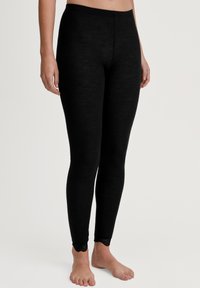 Leggings neri a coste realizzati in materiale morbido ed elastico, con bordo in pizzo a scallop alla caviglia. Texture liscia, design aderente.