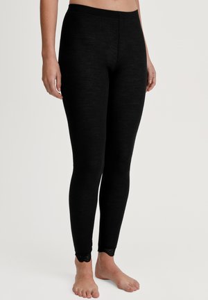 Zwarte geribde leggings van zacht, rekbaar materiaal met gekartelde kantafwerking bij de enkel. Glad textuur, aansluitend ontwerp.
