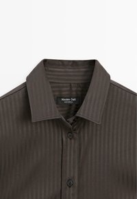 Chemise boutonnée marron foncé avec fines rayures verticales et col classique, étiquette Massimo Dutti, fabriquée au Portugal.