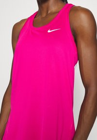 Fuchsiová bezrukávová tank top Nike s kulatým výstřihem, na hrudi s malým bílým logem a hladkým, lehkým materiálem.