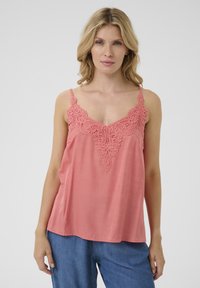 Top breskve barve brez rokavov z nežnimi čipkastimi detajli na izrezu. Mehka tkanina, sproščen kroj, v-izrez in nastavljive naramnice.