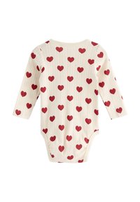 Långärmad baby bodysuit i krämfärg med en strukturerad mönster av röda hjärtan, med tryckknappar i botten och en rund halsringning.