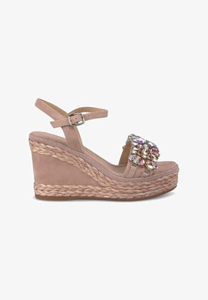 Sandale compensée en suede rose clair avec une semelle en jute tressé. Dispose d'une bride ornée de bijoux avec des accents colorés et d'une boucle à la cheville pour un ajustement.