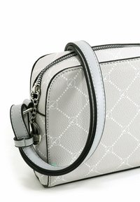 Petit sac à bandoulière en cuir gris clair avec un motif en diamants matelassés, bord noir, et une sangle réglable avec une fermeture éclair et des accessoires en argent.