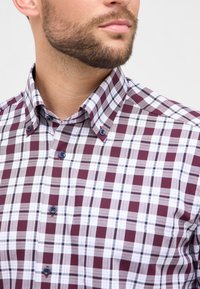 Camicia a quadri in bordeaux, bianco e blu navy. Presenta un colletto button-down, dettagli dei bottoni a contrasto e una texture morbida e liscia.