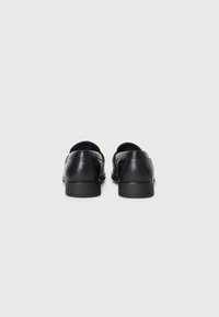 Black leather shoes with a smooth texture, low heel, rounded shape, and no visible accents or hardware, viewed from the rear.