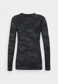 Camisa de mangas longas em cinza escuro com um padrão de camuflagem. Textura suave, gola redonda, apresentando detalhes cosidos ao longo das costuras.