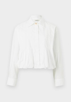 Λευκό μπλούζα με μακριά μανίκια, με πλισέ μέση, κλασικό γιακά, ένα πάνω κουμπί και κρυφά κουμπιά μπροστά.