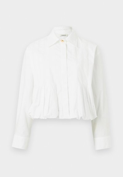 Blouse blanche à manches longues avec taille plissée, col classique, fermeture par un seul bouton supérieur et boutons avant dissimulés.
