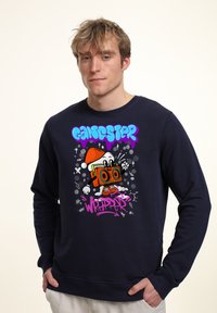 Námořnická modrá mikina s barevným grafickým designem, který zobrazuje kreslenou postavičku, portablvý reproduktor a text "GANGSTER WRAPPER" v živých barvách.