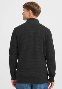 Dunkelgrauer Strickpullover mit hohem Kragen, strukturiertem Stoff, langen Ärmeln und gerippten Bündchen. Die Rückansicht zeigt ein gerade geschnittenes Design.