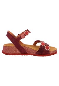 Red leather sandal with circular accents, cork footbed, and textured glitter sole. Adjustable strap provides secure fit.