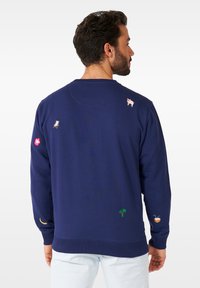 Sudadera azul marino con cuello redondo, material de algodón, con coloridos bordados: un cerdo, una silla, una flor, un plátano, una palmera y un coco.