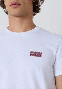 Balta medvilninė marškinėliai su tekstu "AMERICAN VINTAGE" bordo spalvos kairėje krūtinės pusėje. Apvalia kaklo linija, trumpomis rankovėmis, standartinio kirpimo.