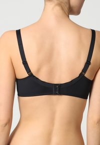 Reggiseno imbottito nero con spalline regolabili, chiusura a gancetto e tessuto liscio. Presenta un design semplice senza ulteriori motivi o accessori.