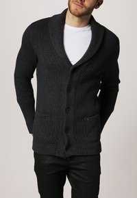 Mörkgrå ribbad cardigan med sjalkrage, med sex knappar, två framfickor och ett strukturerat stickmönster.