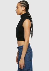 Čierny rebrovaný bezrukávový crop top s vysokým krkom a bočným zipsom, kombinovaný s modrými denimovými šortkami s vysokým pásom a veľkými vreckami.