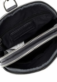 Offene schwarze Stoff- und Lederetui mit sichtbarer innerer Reißverschlusstasche und einem kleinen weißen Etikett innen.