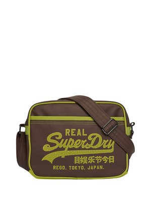 Sac bandoulière rectangulaire marron avec garniture verte et sangle réglable, comportant le texte "Real SuperDry Regd. Tokyo, Japan" en vert.