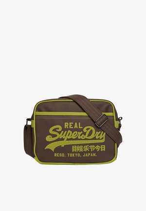 Brązowa prostokątna torba na ramię z zielonym obszyciem i regulowanym paskiem, z zielonym tekstem "Real SuperDry Regd. Tokyo, Japan".