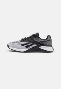 Svart och vit atletisk sko med en texturerad mesh-övre, framträdande logotypaccenter och en dämpad sula med en distinkt form.