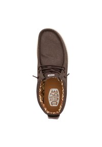 Bruine canvas schoen met een gestructureerde afwerking, voorzien van een witte zool en een bruin patroon aan de binnenvoering. Inclusief veters voor een secure pasvorm.