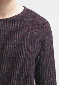 Maglione lavorato a maglia con texture in fibre scure e multicolori. Presenta un collo rotondo e maniche raglan, con una vestibilità casual e un design a maglia stretta.