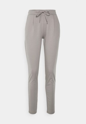 Pantaloni grigi a gamba affusolata realizzati in materiale morbido ed elastico. Presentano una vita con coulisse e pieghe laterali, con una texture liscia in tutto il capo.