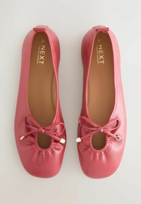 Balerini roz din piele, cu vârf rotund, având un design decupat, elemente elastice adunate și un mic accent cu fundă și detalii metalice.