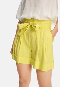 Gelbe plissierte Shorts mit einem breiten Bund und einer gebundenen Schleifen-Detail. Hergestellt aus leichtem Stoff, mit Seitentaschen und einem gesäumten Abschluss.