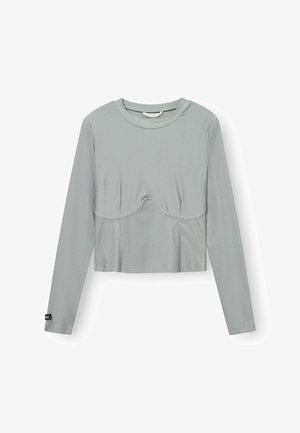 Top court à manches longues en tissu gris clair. Il présente un col rond et un détail de couture courbe subtile à l'avant pour un design supplémentaire.