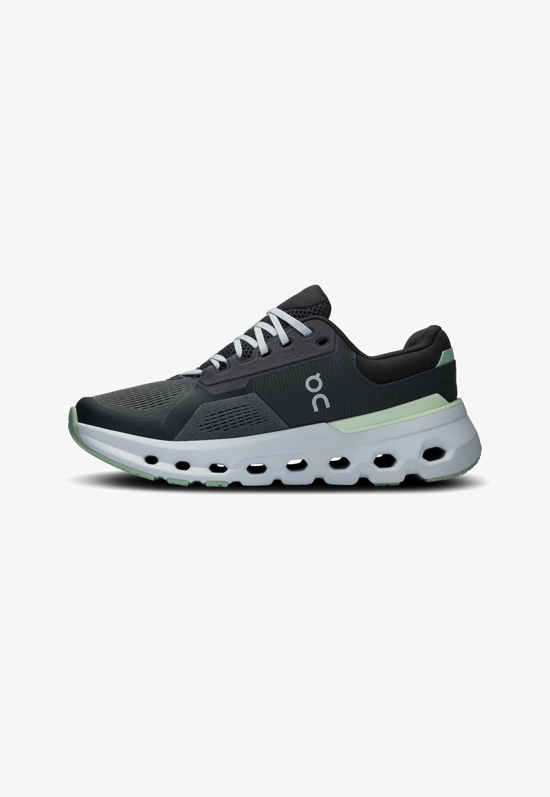 Athletic sneakers featuring a black mesh upper, white laces, and a cushioned sole with green accents and a textured, ventilated design.